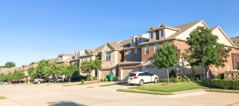 Row of townhouses with brick facades and manicured lawns in a suburban neighborhood