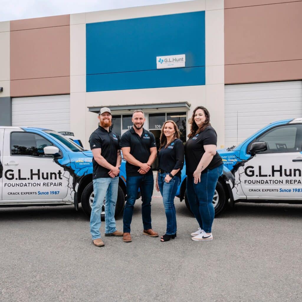 G.L. Hunt Foundation Repair team members standing in front of the company office with branded trucks
