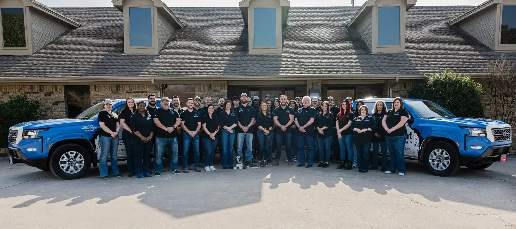 The G.L. Hunt Foundation Repair team standing in front of a house with two branded service trucks