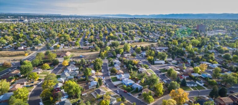 Aerial view of a suburban neighborhood with tree-lined streets and houses stretching toward the horizon