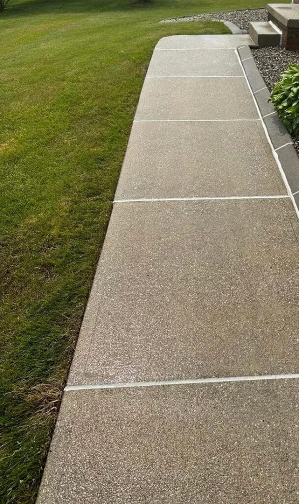 Clean, freshly sealed concrete sidewalk leading to a home's entrance