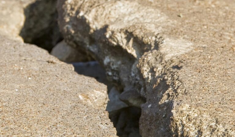 Deep crack in a concrete surface exposing underlying material