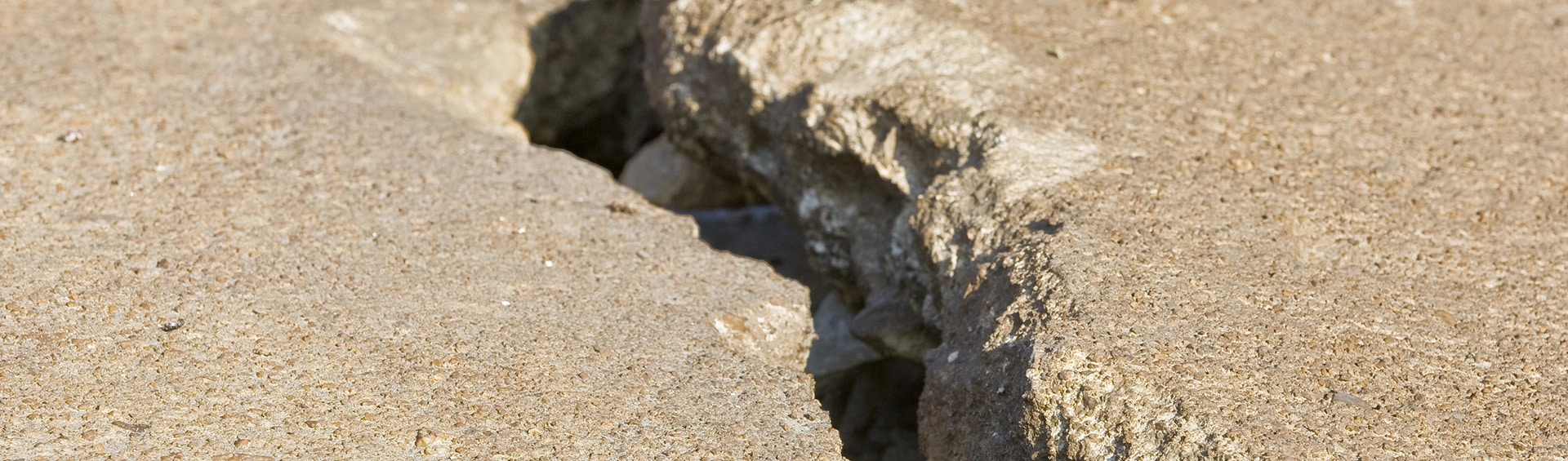 Deep crack in a concrete surface exposing underlying material