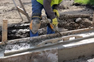 A concrete worker leveling a freshly poured concrete slab during a foundation repair job in Waco, TX.