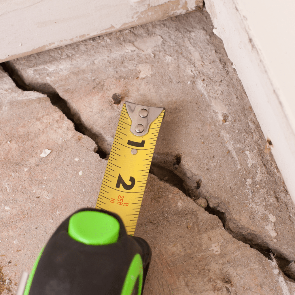 Measuring tape extended over a large crack in a concrete floor