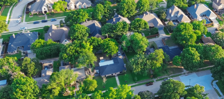 Aerial view of a suburban neighborhood with tree-lined streets and large homes