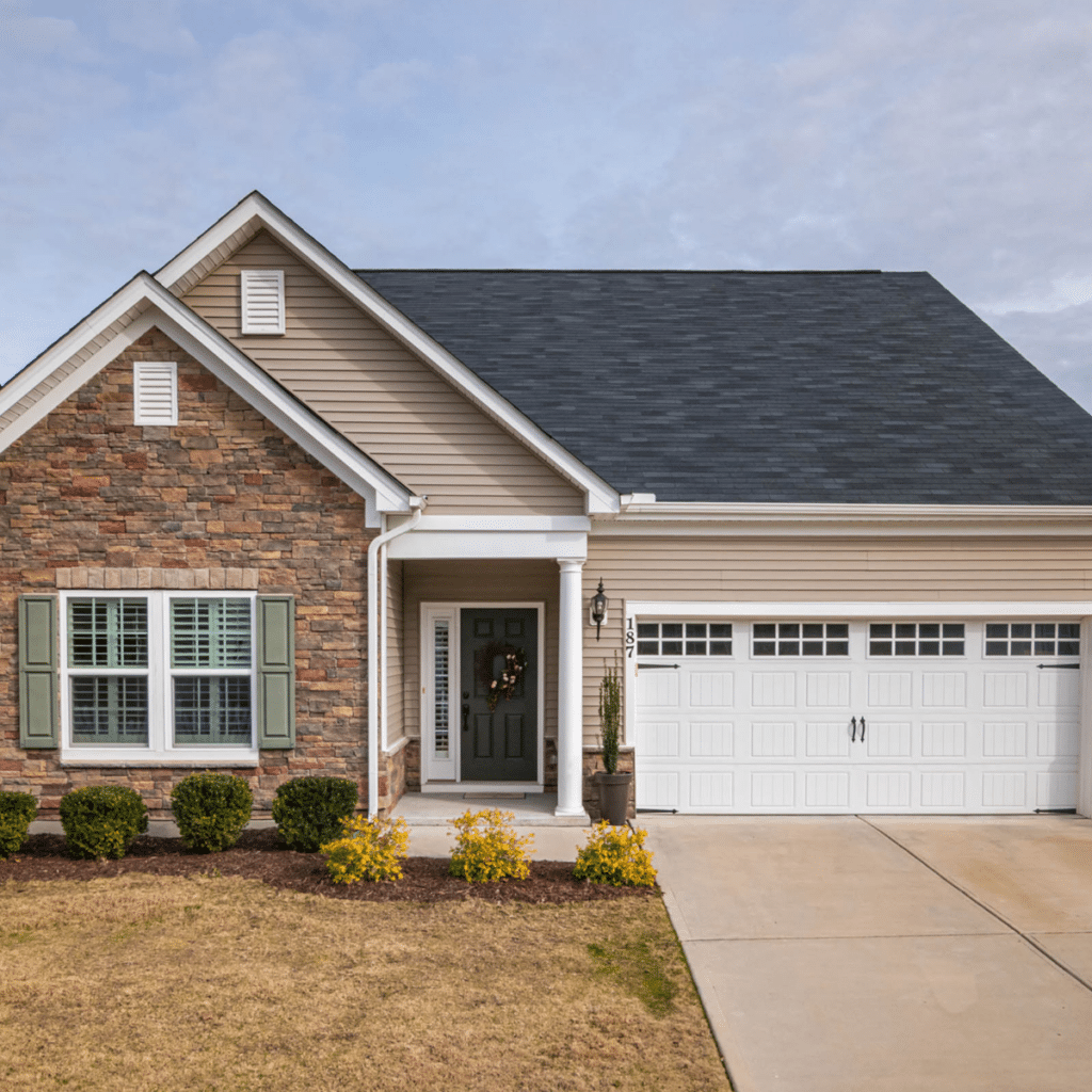 Single-story suburban home with stone and beige siding exterior, a green front door, and a white garage door