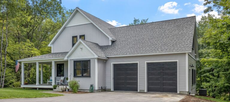 Light gray modern farmhouse with double black garage doors and a front porch