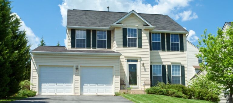 Cream-colored two-story home with black shutters and a two-car white garage