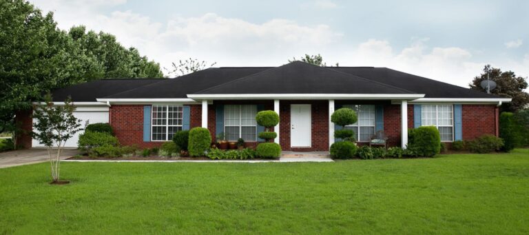 One-story red brick home with blue shutters and manicured front lawn