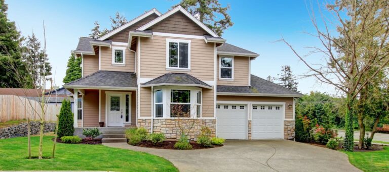 Two-story tan house with stone accents, white trim, and curved driveway