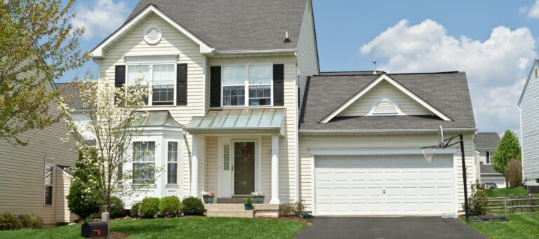 Beige two-story home with white columns, green metal awning, and a basketball hoop