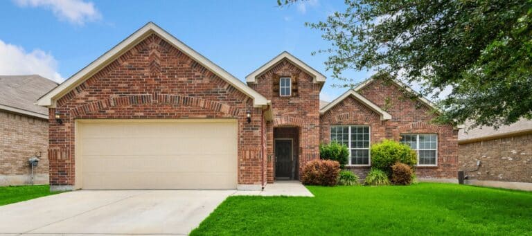 One-story red brick home with a two-car garage and simple, green front lawn