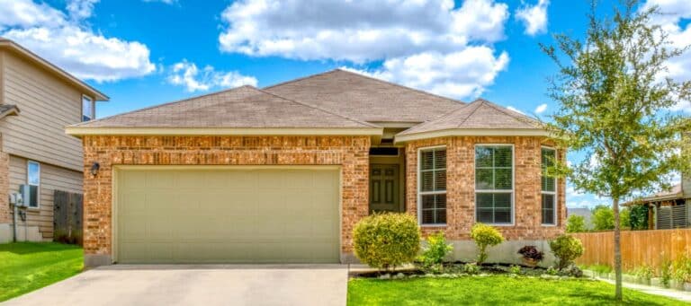Single-story brick house with bay windows, two-car garage, and neatly trimmed landscaping