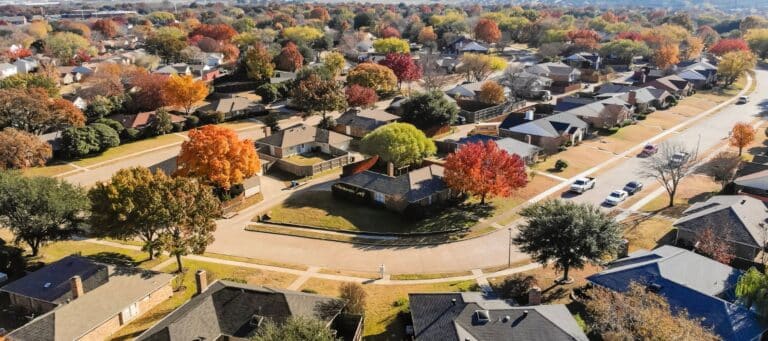Aerial view of a suburban neighborhood in fall with colorful foliage and curving residential streets