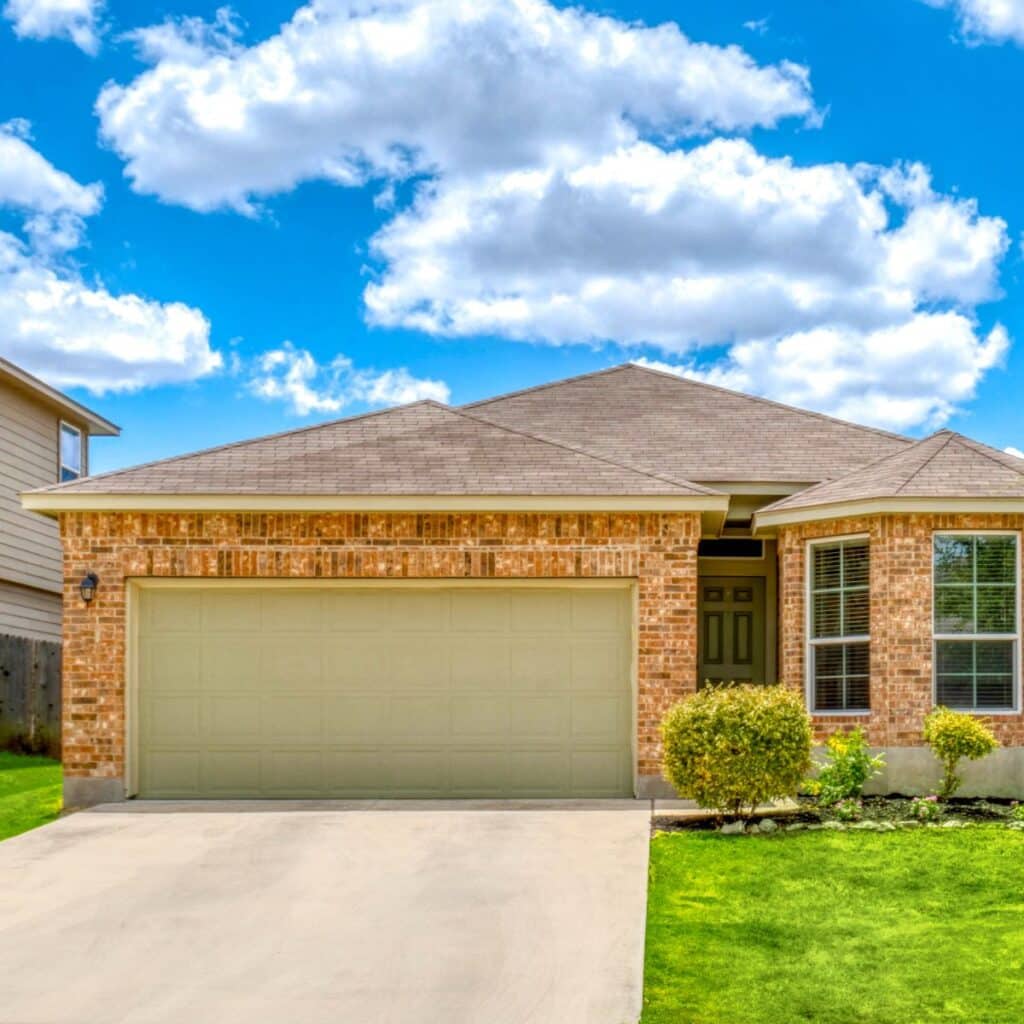 Single-story brick house with bay windows, two-car garage, and neatly trimmed landscaping
