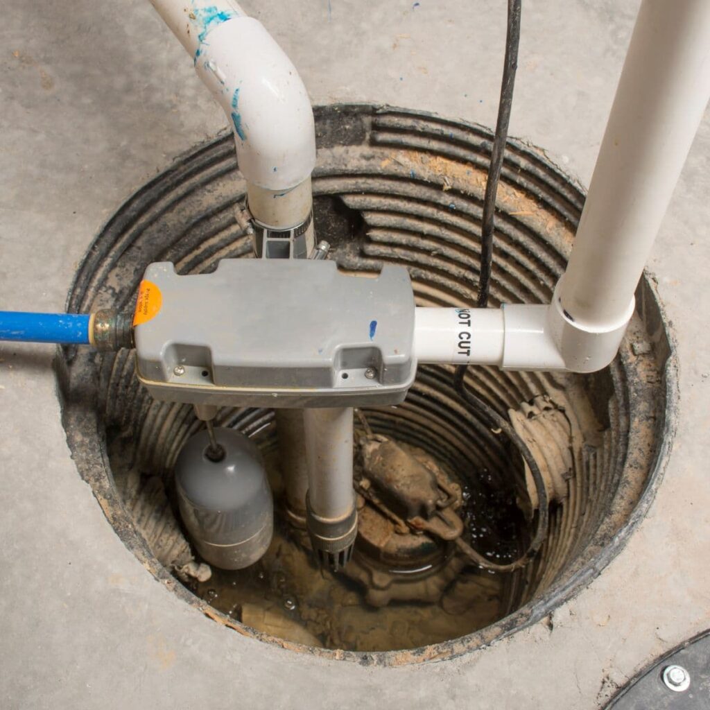 Installed sump pump system with PVC piping in a basement pit used for water drainage