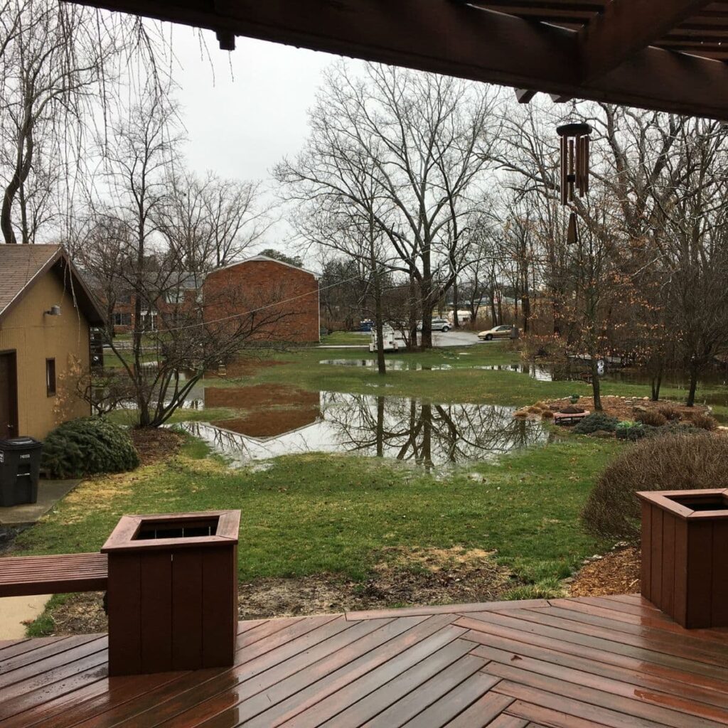 Water pooling along the side of a house, indicating potential foundation drainage issues
