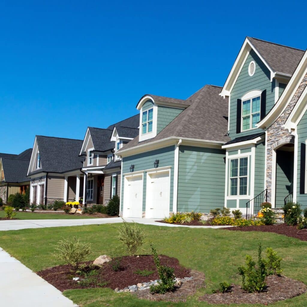 Row of suburban homes with manicured lawns under a clear blue sky