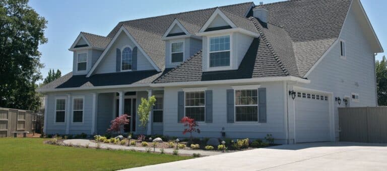 Large modern house with gray siding, white trim, and a landscaped front yard