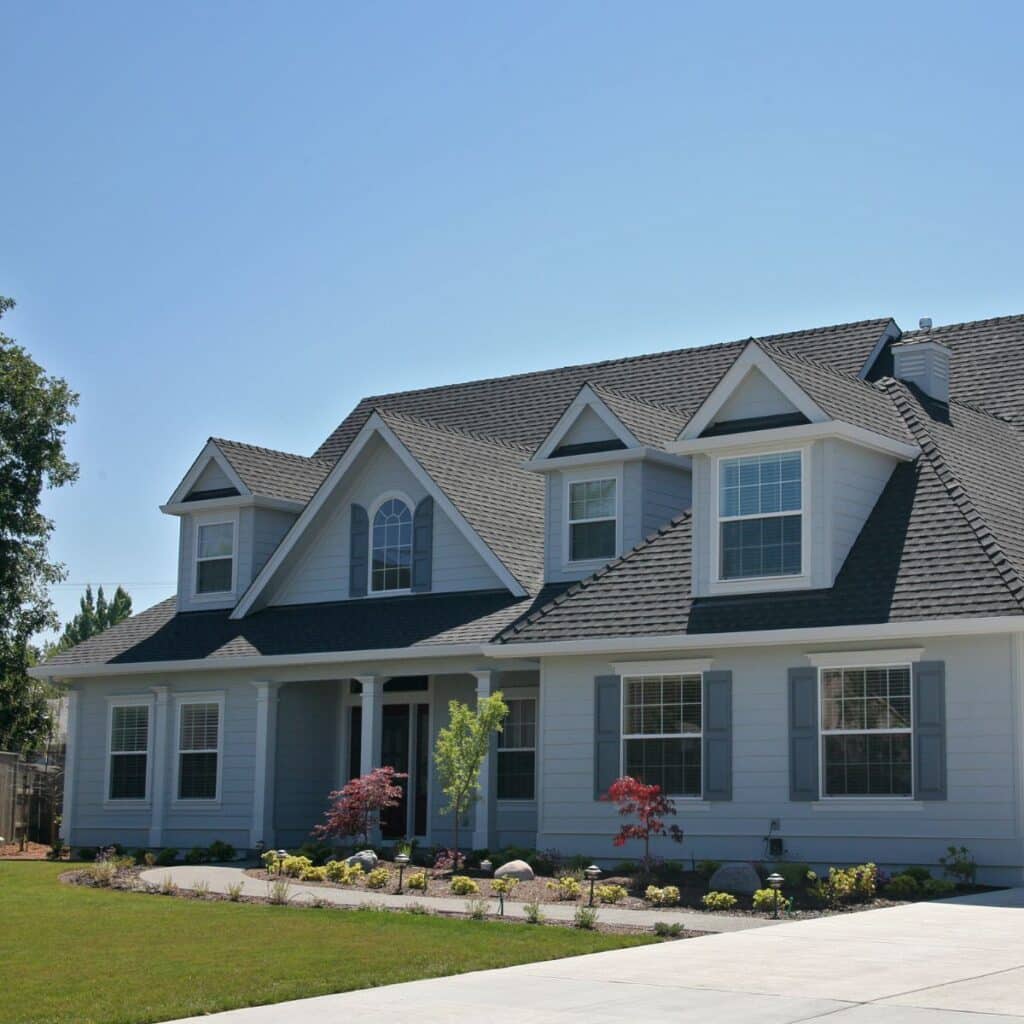 Large modern house with gray siding, white trim, and a landscaped front yard