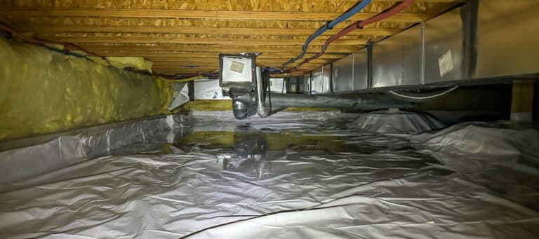 A crawl space shows a clean white vapor barrier covering the ground, with insulation and various pipes and ducts above