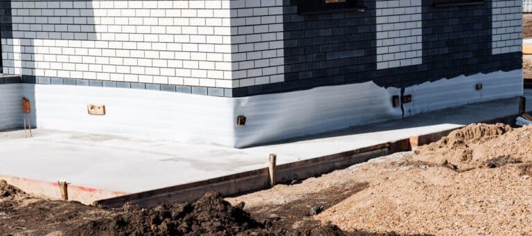 house foundation under construction with fresh concrete base and brick siding