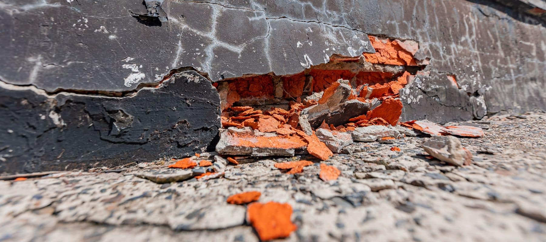 Damaged foundation wall with exposed red brick and crumbling mortar