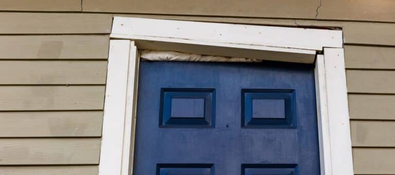 Misaligned door frame above a blue door showing signs of foundation settling
