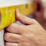 Worker using a level tool on a wall for house leveling