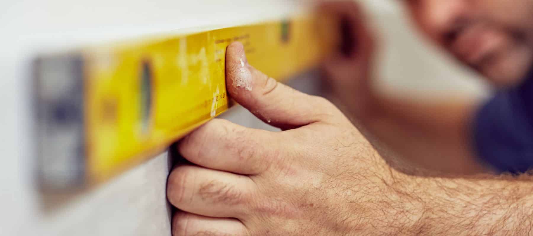 Worker using a level tool on a wall for house leveling