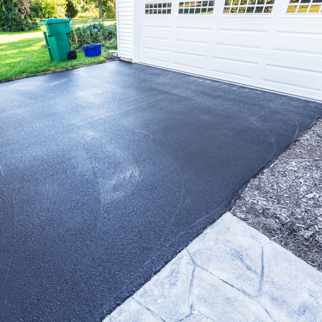 Freshly sealed concrete driveway in front of a residential garage