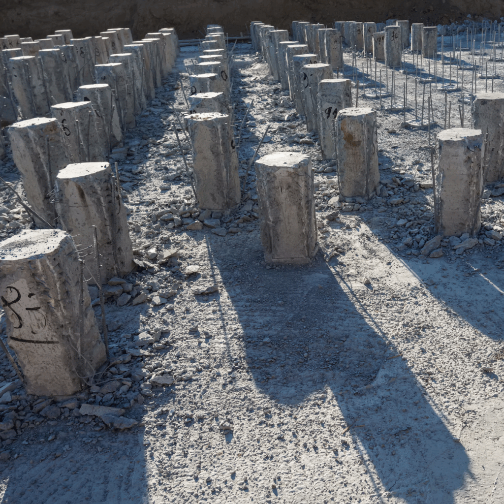 Rows of concrete foundation piers with exposed rebar at a construction site