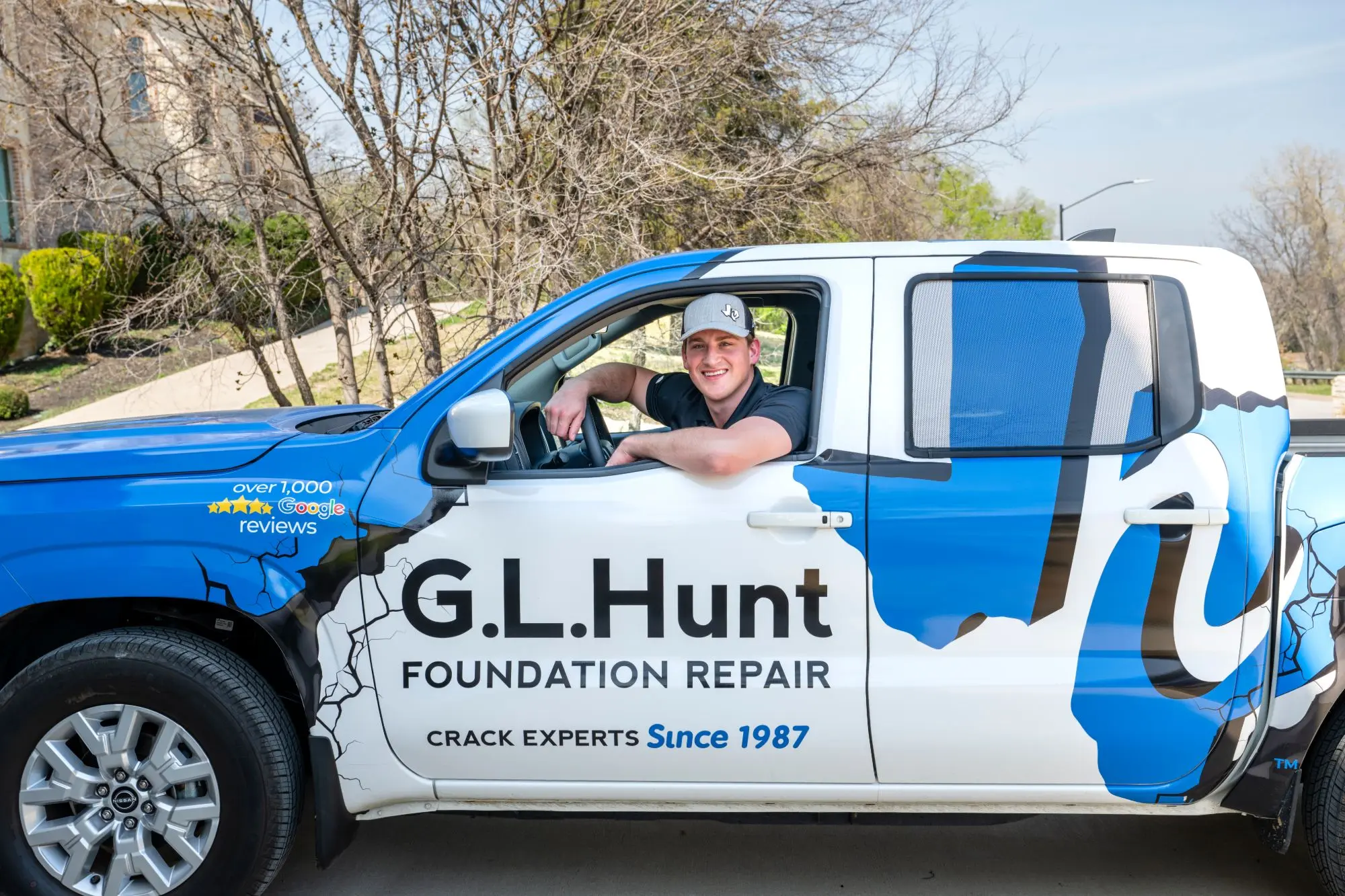 A smiling G.L. Hunt team member in a G.L. Hunt Foundation Repair truck
