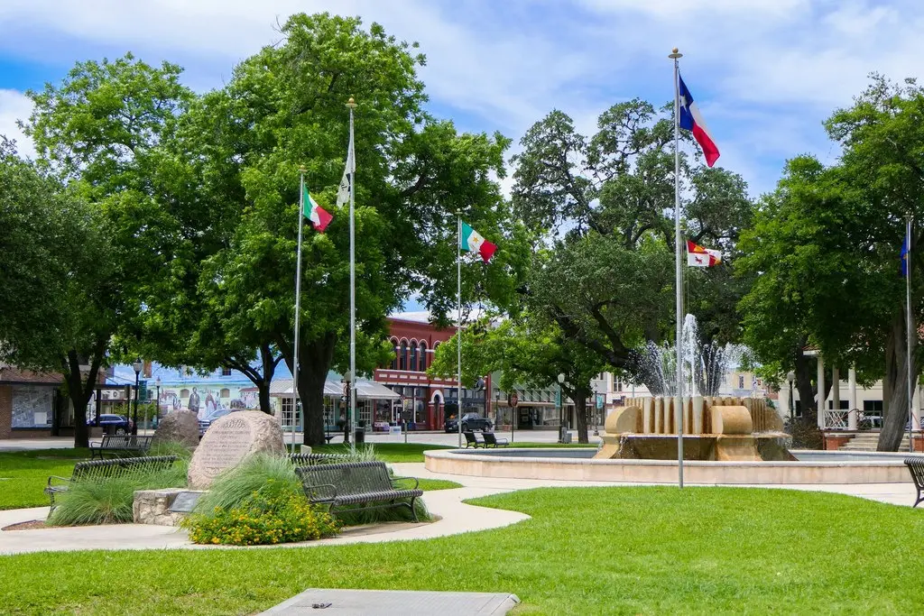 Central Park in downtown Seguin, TX, featuring the Texas flag, a fountain, and the historic courthouse square.